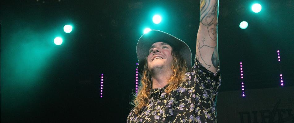 Rebelution vocalist on stage with teal lights